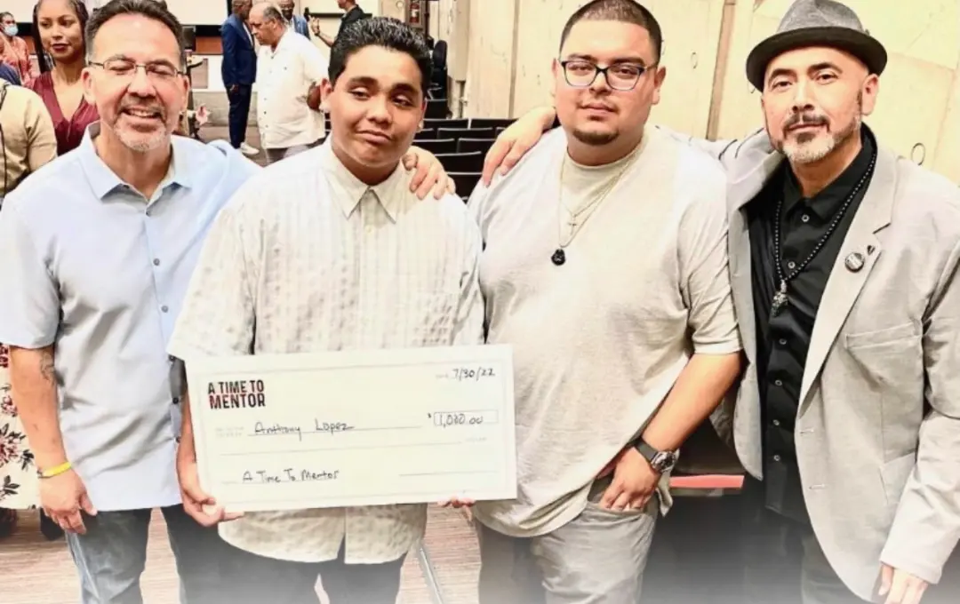 Mentors standing with two young men receiving recognition
